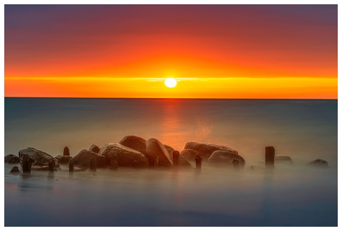 Ein Sonnenuntergang wie gemalt – glühendes Licht trifft auf ruhiges Wasser. Die alte Buhne trotzt den Wellen, während der Tag in Farben explodiert. Ein Moment völliger Stille an der Ostsee, eingefangen in seiner intensivsten Form.