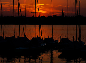Roter Sonnenuntergang und Segelboote an der Alster in Hamburg