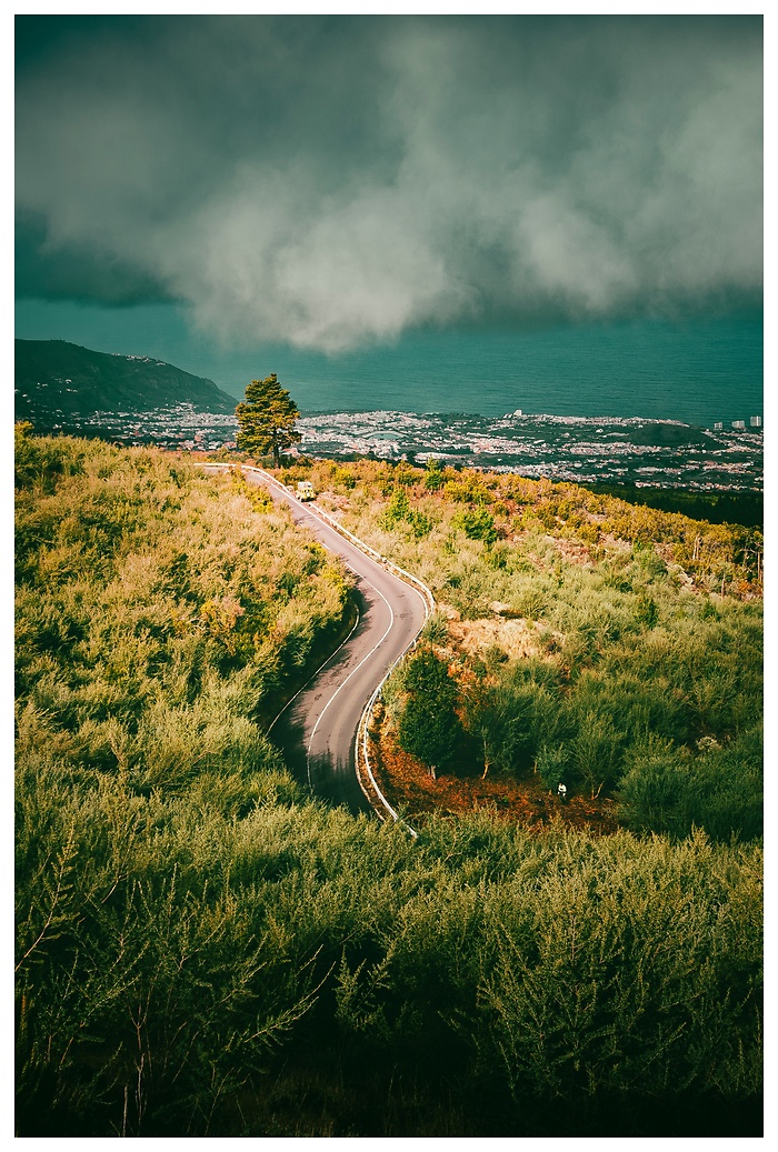 Ein Moment der Ruhe über den Hügeln von Teneriffa. 
Diese Serpentinenstraße führt nicht nur durch die Natur, sondern direkt in den Horizont – mit Aussicht auf das Meer, die Stadt und den Himmel, der Geschichten schreibt.