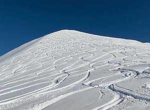 Wavy tracks of snow from skiers and snowboarders down the mountain