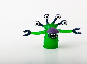 Closeup of a green monster with four eyes and big teeth.
