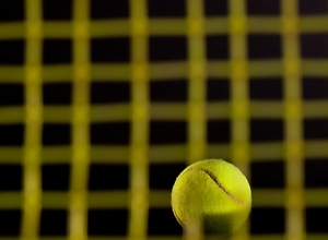 Yellow Tennis ball in front of a dark background.